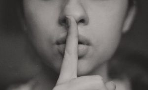 woman holding finger to mouth going sssh